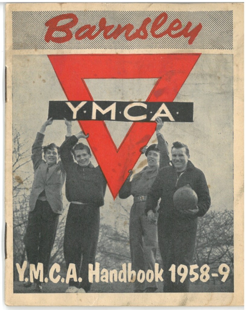 Cover of the Barnsley YMCA handbook 1958-9.  There is a black and white photograph of four young men, one is holding a football and the other three appear to be holding the YMCA logo, which is a red triangle with a black rectangle across the middle which has YMCA on it in white letters. 