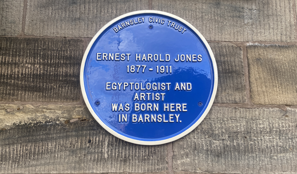 A blue plaque. text reads: Ernest Harold Jones 1877-1911 Egyptologist and artist was born here in Barnsley.