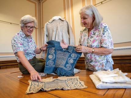 two volunteers working with our textiles collections